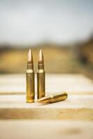 308 caliber ammunition for a rifle standing on a wooden table on the background of the shooting range photo