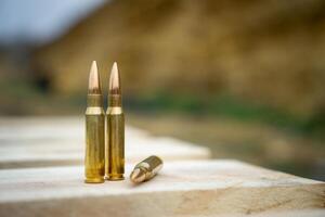 308 caliber ammunition for a rifle standing on a wooden table on the background of the shooting range photo