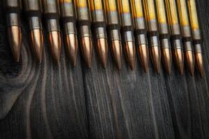 Cartridges for a carbine on a wooden surface. Weapon ammunition on a vintage table. Dark back. photo