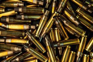 Background from empty cartridges for rifles and carbines. Shiny brass shells scattered on the surface. photo