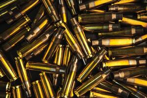 Background from empty cartridges for rifles and carbines. Shiny brass shells scattered on the surface. photo