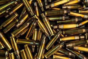 Background from empty cartridges for rifles and carbines. Shiny brass shells scattered on the surface. photo