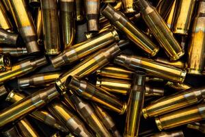 Background from empty cartridges for rifles and carbines. Shiny brass shells scattered on the surface. photo