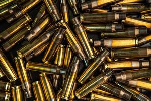 Background from empty cartridges for rifles and carbines. Shiny brass shells scattered on the surface. photo
