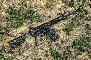 A modern automatic American carbine lying on the ground in the mud. Weapons in extreme conditions. Testing weapons for strength, performance and practicality. photo