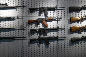Collection of rifles and carbines. Various firearms hang on special mounts on the wall. Weapon back photo