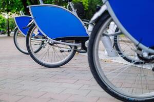 Bicycles for rent are parked in a row. An environmentally friendly and popular form of transport. photo
