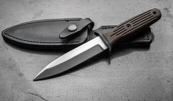 A modern hunting knife and a leather case for him on a dark background. Melee weapons for hunting and self-defense. The instrument of crime. photo