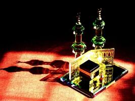 Small model of the Kaaba, the holy mosque of the Grand Mosque, Mecca, isolated on a dark background. There is sunlight coming performing an amazing shadow and shining reflection photo