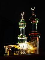 Small model of the Kaaba, the holy mosque of the Grand Mosque, Mecca, isolated on a dark background. There is sunlight coming performing an amazing shadow and shining reflection photo