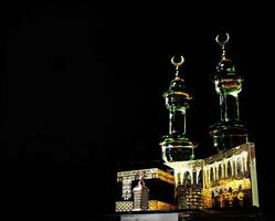 Small model of the Kaaba, the holy mosque of the Grand Mosque, Mecca, isolated on a dark background. There is sunlight coming performing an amazing shadow and shining reflection photo