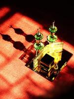 Small model of the Kaaba, the holy mosque of the Grand Mosque, Mecca, isolated on a dark background. There is sunlight coming performing an amazing shadow and shining reflection photo