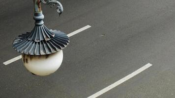 A street light with a white shade is hanging from a pole on the asphalt street road. The light is surrounded by a white line. Copy space for text photo