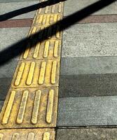 abstract background textured of a long shadow on an embossed yellow line pavement for blind pedestrian. photo