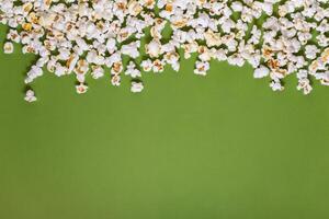 White tasty popcorn on a green background. Popcorn pattern on green background. Top view. Copyspace for your text. photo