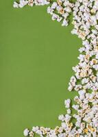 White tasty popcorn on a green background. Popcorn pattern on green background. Top view. Copyspace for your text. photo