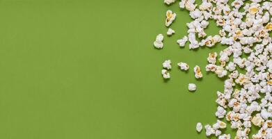 White tasty popcorn on a green background. Popcorn pattern on green background. Top view. Copyspace for your text. photo