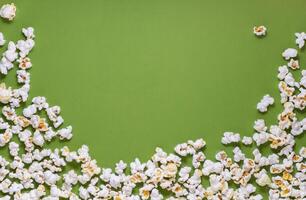 White tasty popcorn on a green background. Popcorn pattern on green background. Top view. Copyspace for your text. photo
