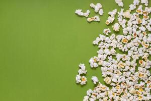 White tasty popcorn on a green background. Popcorn pattern on green background. Top view. Copyspace for your text. photo