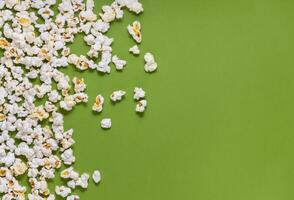 White tasty popcorn on a green background. Popcorn pattern on green background. Top view. Copyspace for your text. photo
