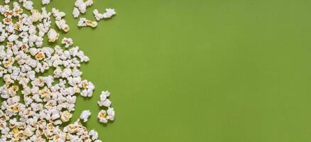 White tasty popcorn on a green background. Popcorn pattern on green background. Top view. Copyspace for your text. photo