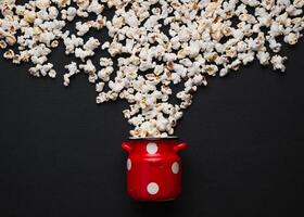 popcorn on a dark background, pouring out of a red can with white polka dots photo