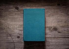 Closed book on vintage wooden background. Old book on the wooden table. Closed book with empty cover laying on wooden table. photo