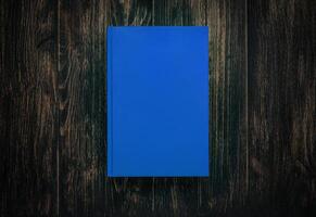 Closed book on vintage wooden background. Book on the wooden table. Closed book with empty cover laying on wooden table. photo