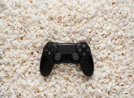 Black gamepad on popcorn back. Game poster or postcard concept. Rest for the game and popcorn. photo