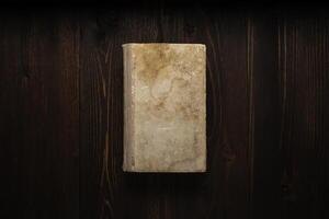 Closed book on vintage wooden background. Old book on the wooden table. Closed book with empty cover laying on wooden table. photo