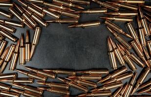 Background from rifle cartridges on a gray metal back. Copy space for text in the center of the image in the form of a rectangle. photo