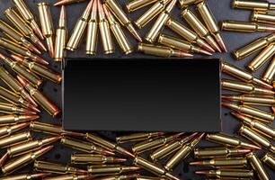Background from rifle cartridges on a gray metal back. A box of cartridges. Copy space for text in the center of the image in the form of a rectangle. photo
