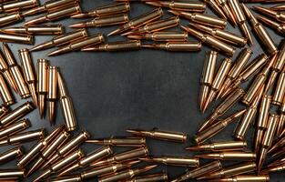Background from rifle cartridges on a gray metal back. Copy space for text in the center of the image in the form of a rectangle. photo