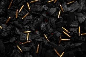 Empty shells from weapons on black smoldering coals. Consequences of the war. Dark back. photo