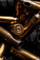 Empty shells from weapons on black smoldering coals. Consequences of the war. Dark back. photo