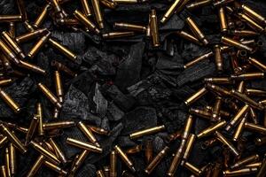 Empty shells from weapons on black smoldering coals. Consequences of the war. Dark back. photo
