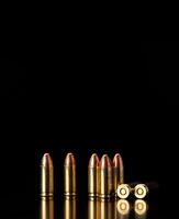 Pistol cartridges 9 mm on a smooth glossy surface with reflections. Ammunition for pistols and PCC carbines on a dark back. photo