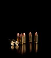 Pistol cartridges 9 mm on a smooth glossy surface with reflections. Ammunition for pistols and PCC carbines on a dark back. photo