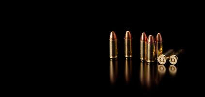 Pistol cartridges 9 mm on a smooth glossy surface with reflections. Ammunition for pistols and PCC carbines on a dark back. photo