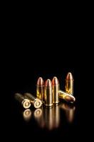 Pistol cartridges 9 mm on a smooth glossy surface with reflections. Ammunition for pistols and PCC carbines on a dark back. photo