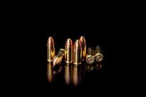 Pistol cartridges 9 mm on a smooth glossy surface with reflections. Ammunition for pistols and PCC carbines on a dark back. photo