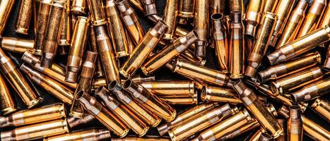 Empty cartridge cases for a carbine or rifle. Background of shiny brass cartridges for cartridges to illustrate armed conflict, war or shooting events. photo