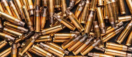 Empty cartridge cases for a carbine or rifle. Background of shiny brass cartridges for cartridges to illustrate armed conflict, war or shooting events. photo