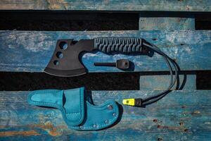 A small black ax with a paracord-wrapped handle. A tool for cutting branches or firewood in the forest. Self defense weapon. Wooden back. photo