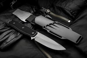 A modern hunting knife with a rubberized handle and a plastic sheath on a dark background. Melee weapons for self-defense and survival. photo