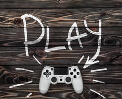 white gamepad on a dark wooden background. word play and an arrow pointing to the gamepad. photo