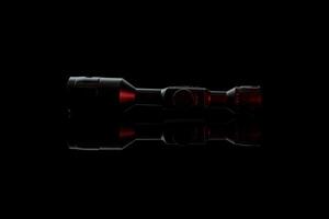 Modern telescopic sight on a smooth mirrored surface. The sight is highlighted in red. A device for shooting at long distances. photo