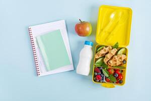 Kids lunch box with zucchini waffles, cucumber, cherry tomatoes and blueberries. Back to school breakfast background. Copy space. Top view, flat lay photo