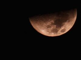 A photo of the half-visible moon taken at night with maximum optical magnification from a mobile phone