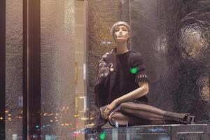 Female mannequin sits in the window of a luxury store and the night lights of the city photo